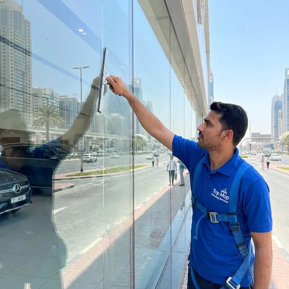Professional cleaner washing a large glass storefront in Dubai