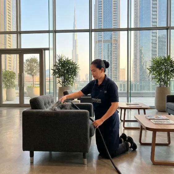 Professional cleaner vacuuming a reception armchair in a modern Dubai interior
